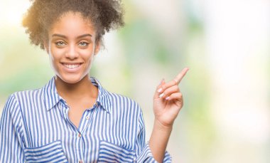 Yüzünde kocaman bir gülümseme ile izole arka plan üzerinde genç afro Amerikalı kadın kameraya bakarak yan el ve parmak ile işaret.