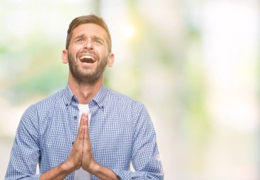 Yalvarıyor ve umut ifade yüzünde çok duygusal ve endişe ile birlikte elleriyle dua izole arka plan üzerinde beyaz t-shirt giyen genç yakışıklı adam. Bağışlanmak. Din kavramı.