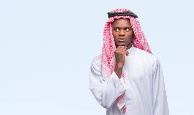 Geleneksel keffiyeh çene düşünme hakkında soru, dalgın ifade üzerine el ile izole arka plan üzerinde giyen genç Arapça Afrika adam. Düşünceli yüzüyle gülümsüyor. Şüphe kavramı.