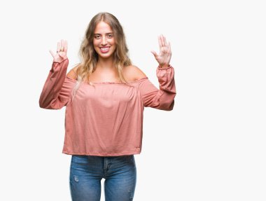 Gösterilen ve parmakları ile işaret izole arka plan üzerinde sarışın güzel genç kadın numara 9 kendinden emin ve mutlu gülümseyerek süre.