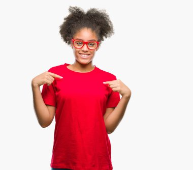 Yüzünde gülümseme ile kendinden emin görünüyorsun, kendini gururlu ve mutlu parmakları ile işaret izole arka plan üzerinde gözlük takan genç afro Amerikalı kadın.