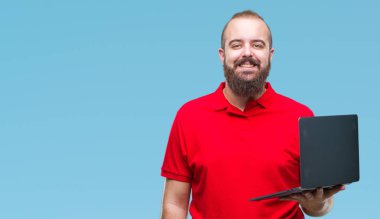 Beyaz delikanlı bilgisayar dizüstü izole arka plan üzerinde duran ve diş gösterilen kendine güvenen bir gülümsemeyle gülümseyerek mutlu bir yüz ile kullanma