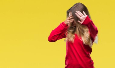 Üzerinde kırmızı kazak giyen genç güzel sarışın kadın izole elleriyle gözlerini kapsayan arka plan ve stop jest ile acı ve korku ifadesi. Utandım ve negatif kavramı.