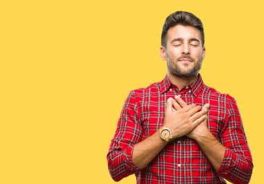 Yakışıklı delikanlı ile gülümseyen izole arka plan üzerinde kapalı gözler ve yüzünde minnettar jest ile göğüs üzerinde eller. Sağlık kavramı.