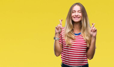 Genç güzel sarışın kadın geçiş parmakları umut ve gözleri kapalı ile gülümseyen izole arka plan yüzünden. Şans ve batıl kavramı.