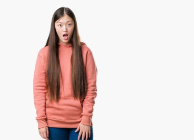 Spor sweathshirt korkuyor ve şok sürpriz ifade, korku ve heyecan yüz ile giyen izole arka plan üzerinde Genç Çinli kadın.