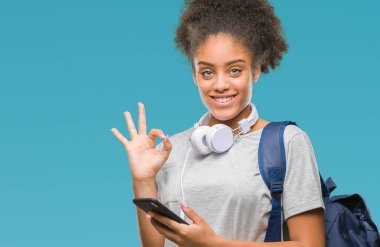 Sırt çantası parmak, mükemmel sembolü ile ok işareti yapıyor izole arka plan üzerinde tutan genç güzel afro Amerikan öğrenci kadın