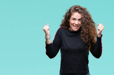 Rahat giyen güzel genç esmer kıvırcık saçlı kız şaşırmış ve başarı için hayran kaldırdı kollarını açarak kutlama izole arka plan üzerinden bakmak ve gözleri açık. Kazanan kavramı.