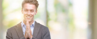 El ele tutusun AF emin gülümseyen için soran ile dua genç yakışıklı sarışın iş adamı.