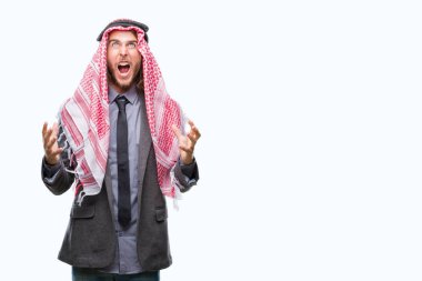 Genç yakışıklı Arap adam uzun saçlı izole arka plan çılgın ve kızgın bağırarak ve agresif ifade ve silah kaldırdı bağırmaya keffiyeh giyiyor. Hayal kırıklığı kavramı.