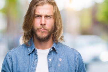 Yakışıklı delikanlı izole arka plan şüpheci ve sinir, papatyanın üzgün sorun nedeniyle uzun saçlı. Negatif kişi.