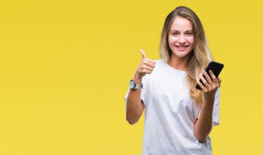 Ok işareti, başparmak ile parmak, mükemmel işareti yapıyor kocaman bir gülümseme ile izole arka plan üzerinde mutlu Smartphone kullanan genç güzel sarışın kadın
