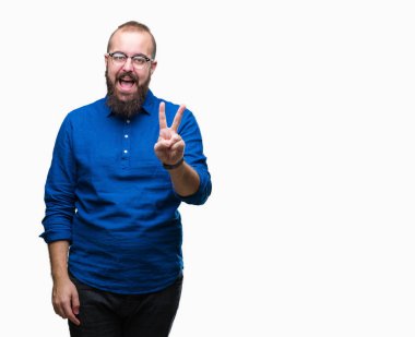 Mutlu yüz zafer işareti yaparken kameraya göz kırpıyor ile gülümseyen izole arka plan üzerinde gözlük takan Genç beyaz hipster adam. İki numaralı.