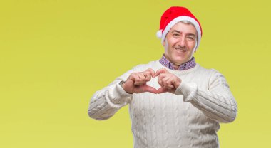 Aşık kalp simgesi ve elleriyle şekil gösteren gülümseyen izole arka plan üzerinde Noel şapka giymiş yakışıklı komuta sizde. Romantik kavramı.