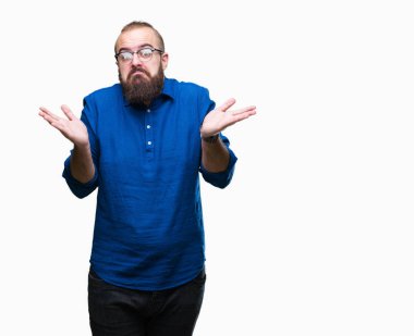 Üzerinde gözlük takan Genç beyaz hipster adam arka plan clueless ve şaşkın bir ifadeyle kollar ve eller kaldırdı izole. Şüphe kavramı.