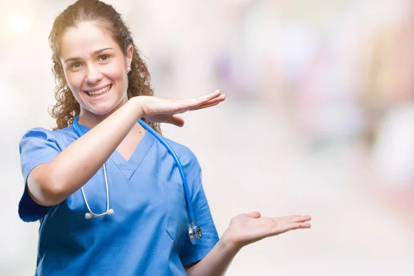 年轻的黑发医生女孩穿着护士或外科医生制服在孤立的背景手势与手显示大和大尺寸的标志 测量符号 看着镜头微笑 测量概念 — 图库照片