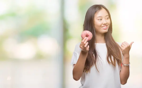 Joven Asiático Mujer Comer Donut Sobre Aislado Fondo Apuntando Mostrando — Foto de Stock