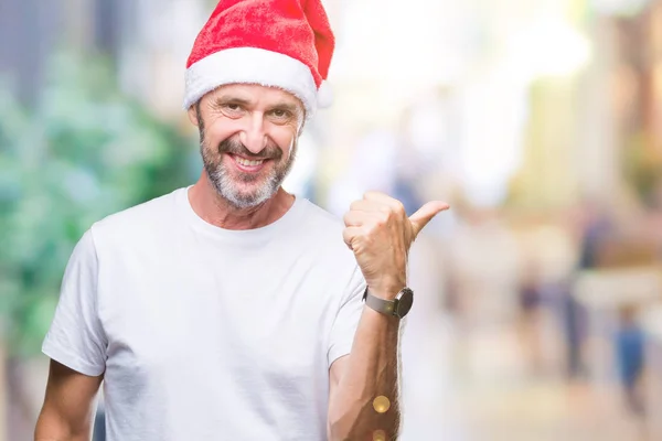探していると親指側に上向きの幸せそうな顔を浮かべて隔離された背景にクリスマスの帽子を着て中年白髪年配の男性 — ストック写真
