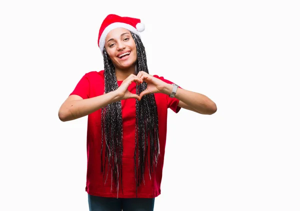 年轻的编织头发非洲裔美国女孩戴着圣诞帽在孤立的背景微笑着在爱中显示心脏符号和形状与手 浪漫的概念 — 图库照片