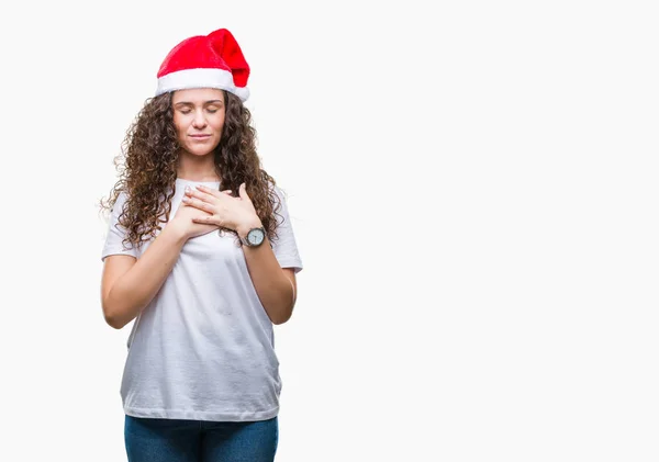 年轻的黑发女孩戴着圣诞帽在孤立的背景微笑着双手在胸前闭着眼睛 脸上带着感激的手势 健康理念 — 图库照片