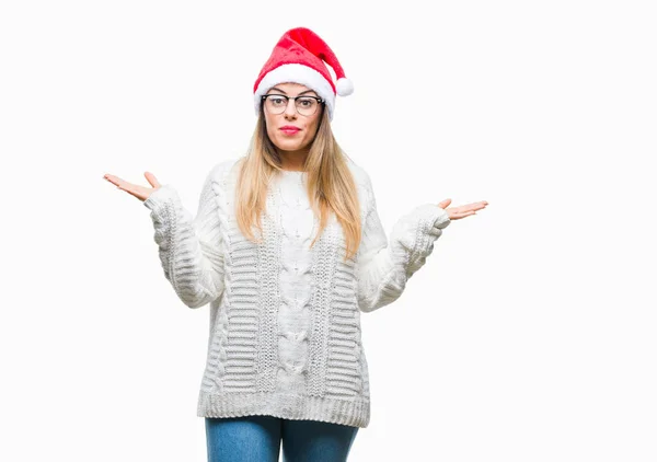 若い美しい女性の腕と手を上げて分離背景無知と混乱する式でクリスマス帽子をかぶっています 疑いのコンセプト — ストック写真