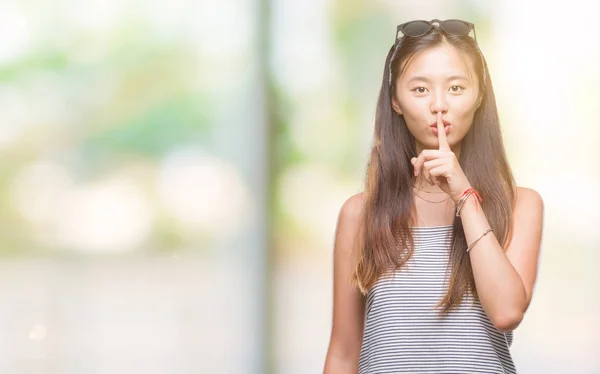 年轻的亚洲妇女戴着太阳镜在与世隔绝的背景下 要求用手指在唇上安静 沉默和秘密概念 — 图库照片