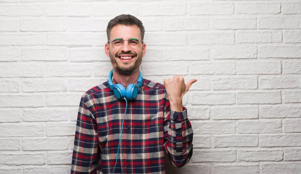 Homem Adulto Jovem Sobre Parede Tijolo Usando Fones Ouvido Apontando — Fotografia de Stock