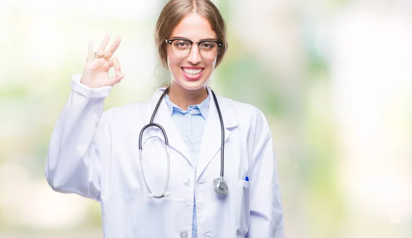美丽的年轻的金发医生妇女穿医疗制服在孤立的背景微笑积极做 标志与手和手指 成功表达式 — 图库照片
