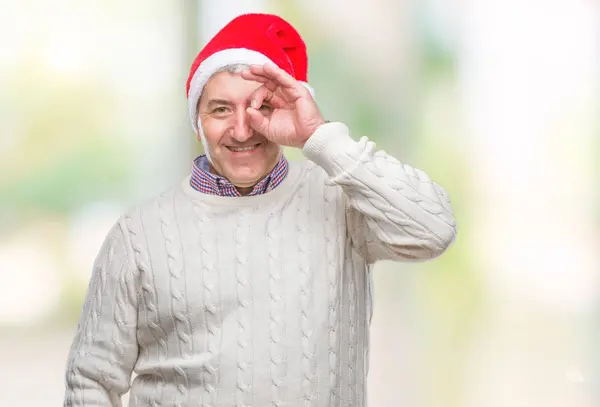 英俊的老人戴着圣诞节帽子在孤立的背景做 手势与手微笑 眼睛看通过手指与幸福的脸 — 图库照片