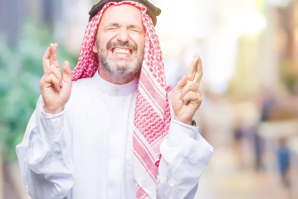 シニアのアラブ人笑顔希望と目を閉じて交差指分離の背景にクーフィーヤを着用します 運と迷信的な概念 — ストック写真