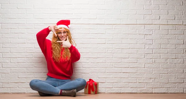 Young Redhead Woman Sitting Brick Wall Wearing Christmas Hat Smiling — Stock Photo, Image