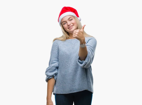 若い白人女性のハッピー サムズアップ手でジェスチャーをして孤立した背景にクリスマス帽子をかぶっています 成功を示すと カメラを見て式を承認します — ストック写真