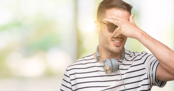 Bonito Jovem Vestindo Fones Ouvido Espreitando Choque Cobrindo Rosto Olhos — Fotografia de Stock