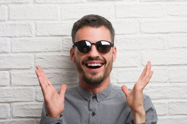 Homem Adulto Jovem Usando Óculos Sol Sobre Parede Tijolo Branco — Fotografia de Stock