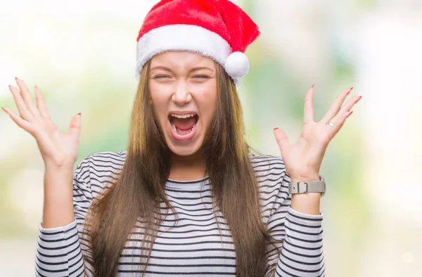 若い美しい白人女性にクリスマスの帽子をかぶって狂気を祝う背景を分離した腕を上げると成功のためびっくりし 叫んで興奮して目を開きます 勝者の概念 — ストック写真