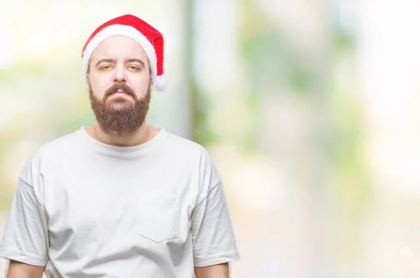 若い白人ヒップ男の顔に真剣な表情で孤立した背景にクリスマス帽子をかぶっています シンプルで自然なカメラを見てください — ストック写真