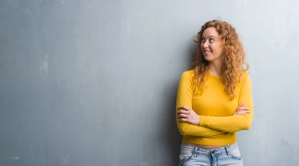 Joven Pelirroja Mujer Sobre Gris Grunge Pared Sonriendo Mirando Lado — Foto de Stock