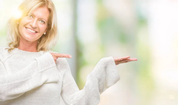 冬のセーターを着て中年金髪女性分離驚くし 手とを提示 指で指している間カメラに笑顔の背景 — ストック写真