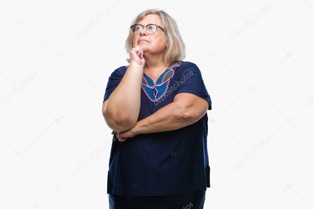 Senior plus size caucasian woman wearing glasses over isolated background with hand on chin thinking about question, pensive expression. Smiling with thoughtful face. Doubt concept.