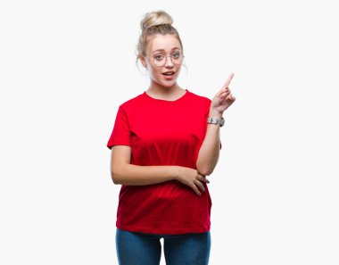 Kameraya bakarak yan el ve parmak ile işaret yüzünde kocaman bir gülümseme ile izole arka plan üzerinde gözlüklü sarışın genç kadın.