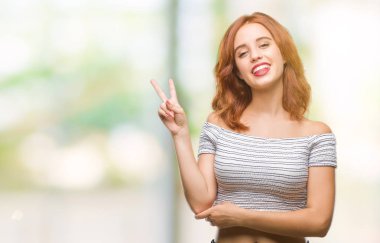 Genç güzel kadın mutlu yüz zafer işareti yaparken kameraya göz kırpıyor ile gülümseyen izole arka plan yüzünden. İki numaralı.