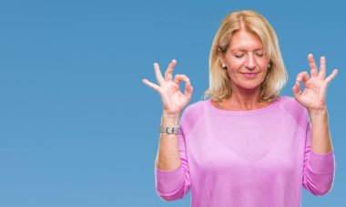 Orta yaş sarışın kadın izole arka plan üzerinde dinlenmek ve gülümseyen gözlerle parmak ile meditasyon jest yapıyor kapalı. Yoga kavramı.
