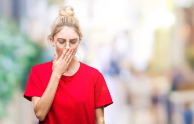 Kırmızı t-shirt ve gözlük izole arka plan üzerinde giyen genç güzel sarışın kadın el ağzıyla kapsayan yorgun esneme sıkılmış. Restless ve uyku hali.