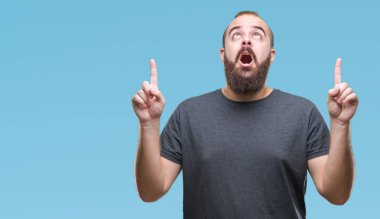 Genç beyaz hipster adam izole arka plan üzerinden hayran ve yukarıya bakıp parmakları ile işaret şaşırttı ve silah kaldırdı.