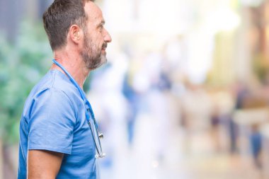 İzole arka tarafına, seyir üzerinde tıbbi üniforma giyen orta yaş ağarmış kıdemli Doktor adam sakin ol kendine güvenen gülümseme ile doğal yüz pozuyla profili.