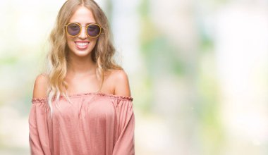 Yüzünde mutlu ve güzel bir gülümseme ile izole arka plan üzerinde Retro güneş gözlüğü takıyor güzel sarışın genç kadın. Şanslı kişi.