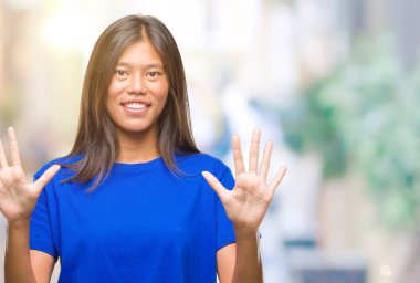 Genç Asyalı kadın gösterilen ve parmakları ile işaret izole arka plan üzerinde kendinden emin ve mutlu gülümseyerek süre on numara.