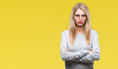 İzole arka plan şüpheci ve çapraz kolları olan yüzündeki gergin, onaylamayan ifade gözlüklü genç güzel sarışın bir kadın. Negatif kişi.