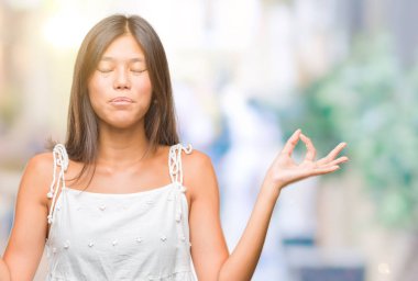 Genç Asyalı kadın izole arka plan üzerinde dinlenmek ve gülümseyen gözlerle parmak ile meditasyon jest yapıyor kapalı. Yoga kavramı.