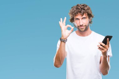 İspanyol yakışıklı model parmak, mükemmel sembolü ile ok işareti yapıyor izole arka plan üzerinde smartphone kullanarak gönderme mesaj manifatura